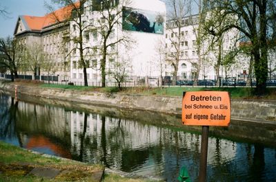 Signboard by canal against buildings