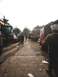 Rear view of people working on street in city against clear sky