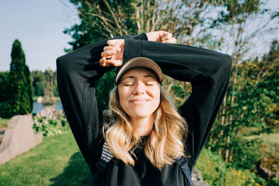 Woman sat in the countryside smiling soaking up the sunshine