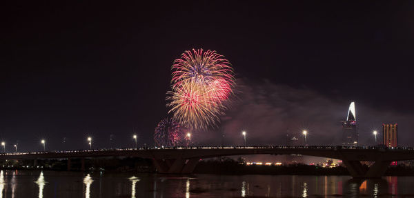 Low angle view of firework display over river at night