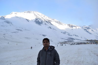 Man standing on snowcapped mountain against sky