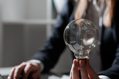 Midsection of woman holding light bulb