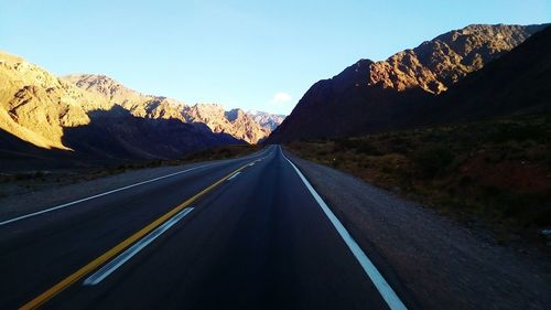 Road amidst mountains against clear sky