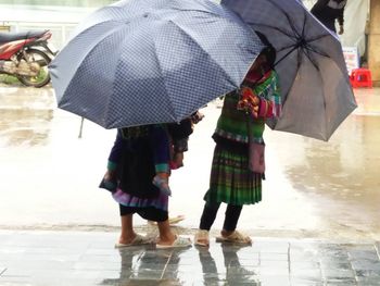 Low section of women walking on wet street during monsoon