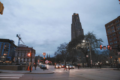 City street by buildings against sky at dusk