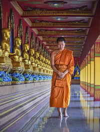 Monk standing by statues in temple