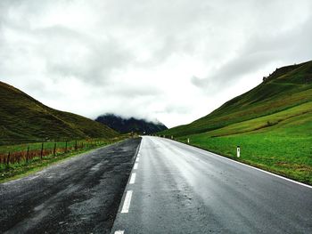 Road amidst green landscape against sky