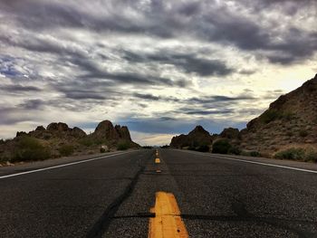 Empty road against cloudy sky