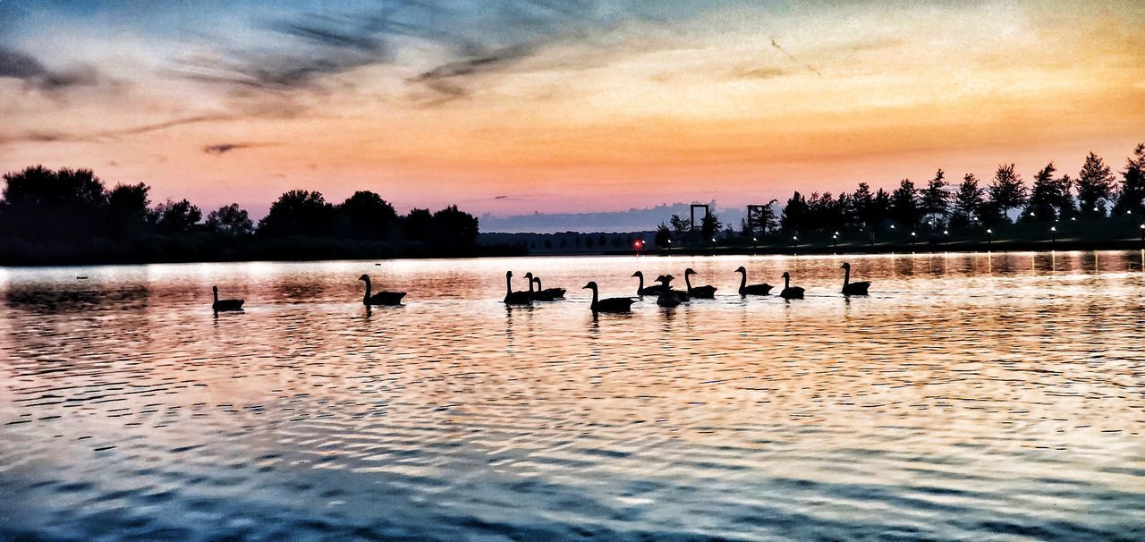 SILHOUETTE PEOPLE ON LAKE AGAINST ORANGE SKY