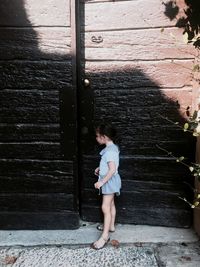 Full length of woman standing against door