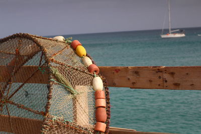 Close-up of fishing net hanging on rope against sea