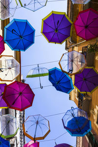 Low angle view of umbrellas hanging against blue sky