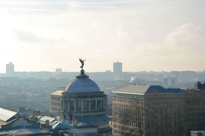 Statue in city against sky