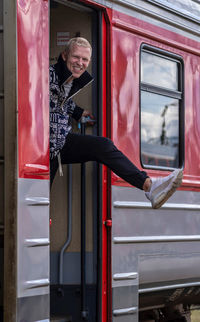 Full length of a man standing in a train with the lifted leg