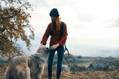 Man with dog standing on field against sky