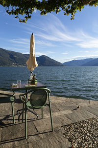 Chairs and table by sea against sky