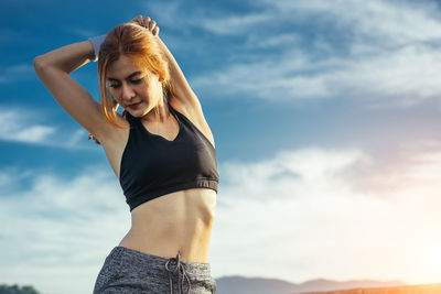 Young woman standing against sky