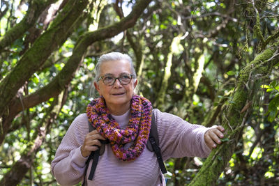 Smiling senior woman against plants