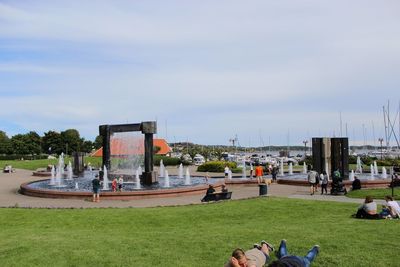 People relaxing at park against sky