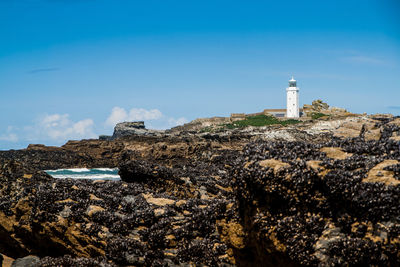 Lighthouse on beach against sky