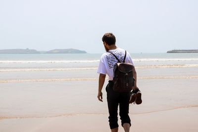 Rear view of man at beach against clear sky