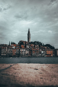 View of buildings at waterfront against cloudy sky