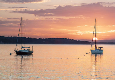 Sailboat sailing on sea against sky during sunset