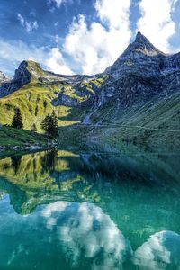 Scenic view of lake by snowcapped mountains against sky