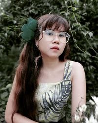 Portrait of young woman standing against trees