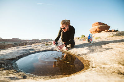 Hiker collects drinking water from a shallow puddle in the desert