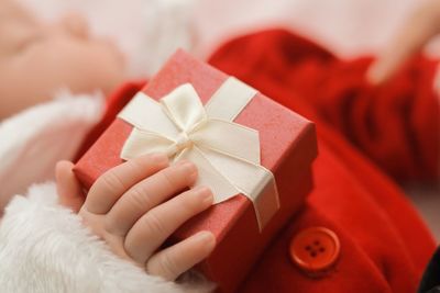Close-up of baby girl wearing santa claus costume holding gift box
