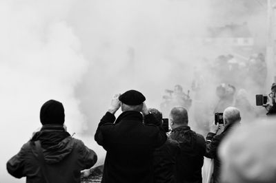 Rear view of people against sky with smoke 