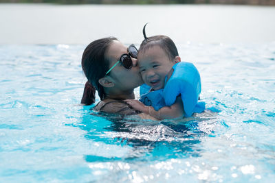 Mother kissing daughter in swimming pool