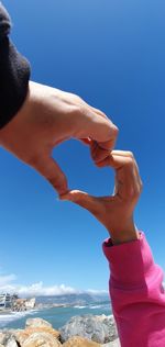 Close-up of hand holding umbrella against clear blue sky