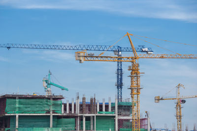 Cranes at construction site against sky