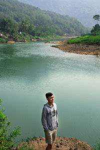 Young man looking at lake against mountain