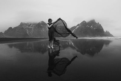 Woman in dress with waving cape on beach monochrome scenic photography