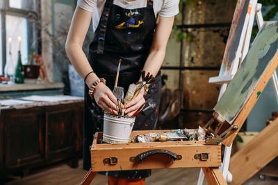 Painter working in real studio with oil paints and brushes, creating canvas, modern art. young woman