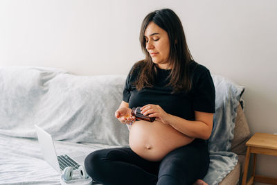 A pregnant woman who cares about the health of her baby consumes vitamins while sitting at home.