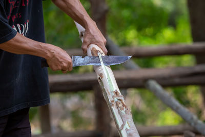 Close-up, a man's hand was using a steel knife sheathed the bark of eucalyptus wood  house design