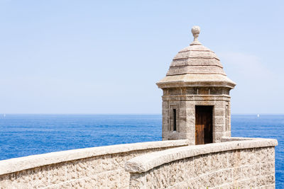 View of castle by sea against clear sky