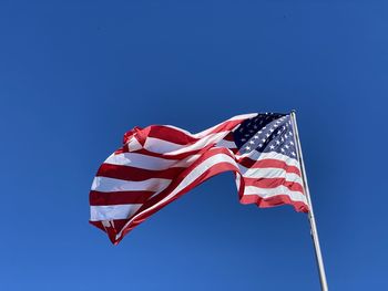 Low angle view of american flag against clear blue sky