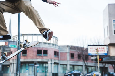 Low section of man skateboarding against clear sky