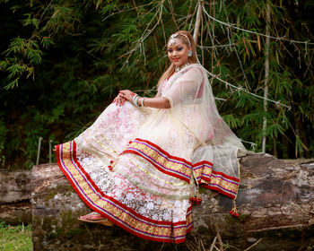 Smiling mid adult woman sitting on log in forest