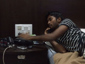 Side view of young man using mobile phone at home