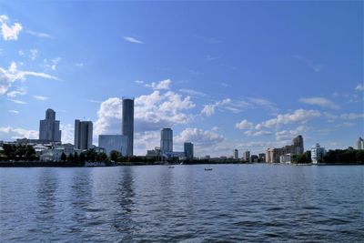 Cityscape by river against sky