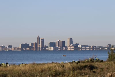 Sea by cityscape against clear sky