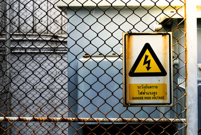 Close-up of warning sign on chainlink fence