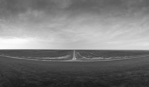 Road amidst field against sky