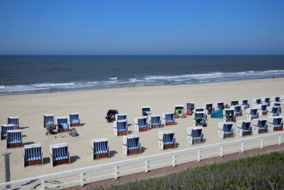 High angle view of hooded chairs on beach against clear sky